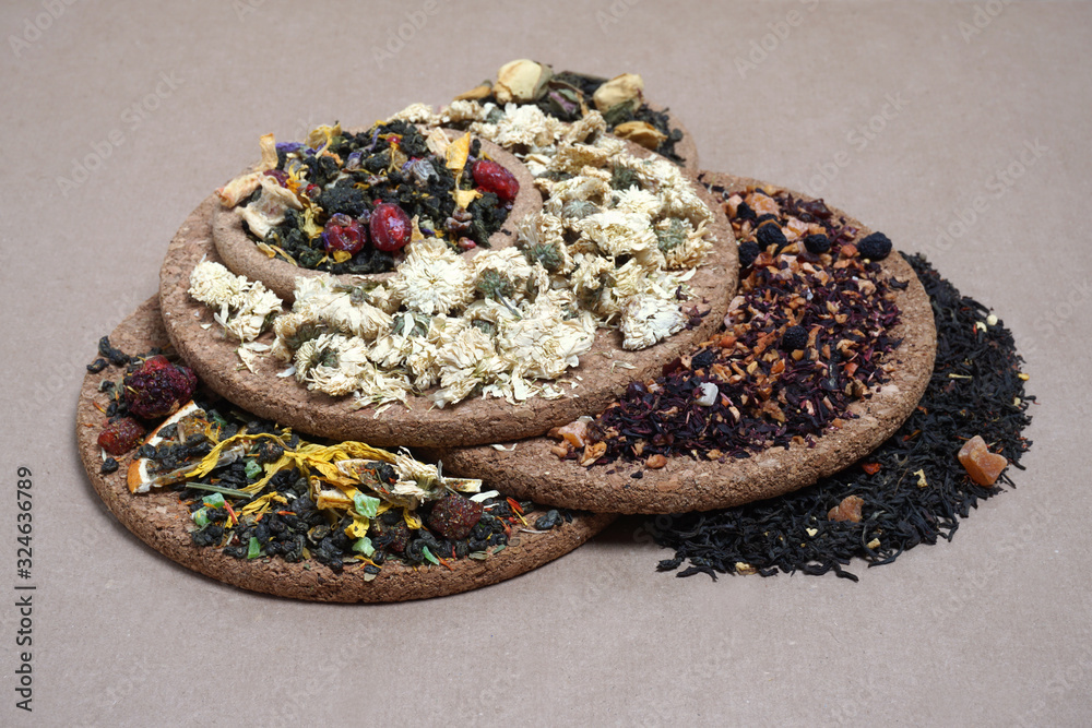 assortment of dry tea on kraft paper and cork coasters. Concept for tea shop, tea house. A variety of types of tea. assortment of dry tea on kraft paper and cork coasters. Concept for tea shop, tea house. A variety of types of tea.