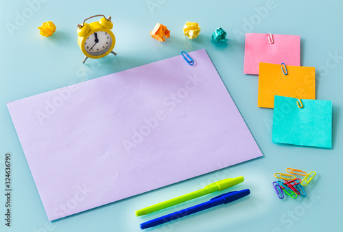 A yellow alarm clock, along with colorful, blank note cards.  Colorful office staples, washed out paper balls, Space for an inscription, 