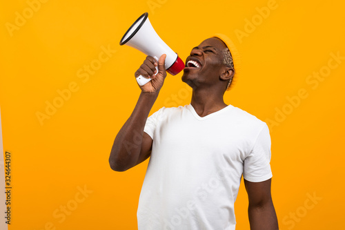 black african man speaks in megaphone on isolated orange background