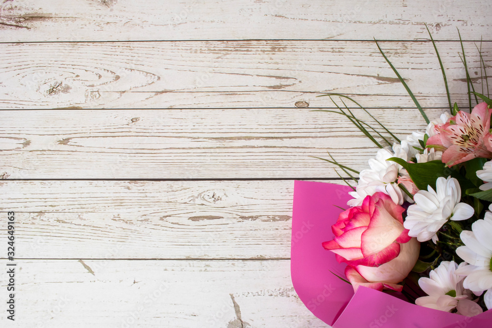 Fototapeta premium Beautiful festive bouquet in pink paper on a white wooden background