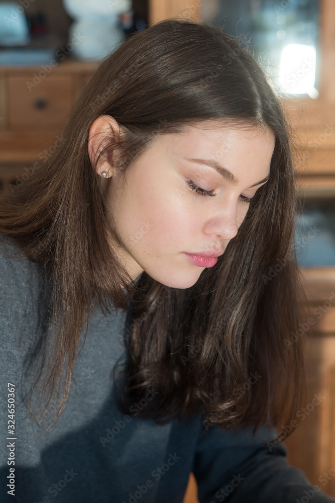 Young woman looking down absorbed in her own thoughts or concentrating Young woman looking down absorbed in her own thoughts or concentrating