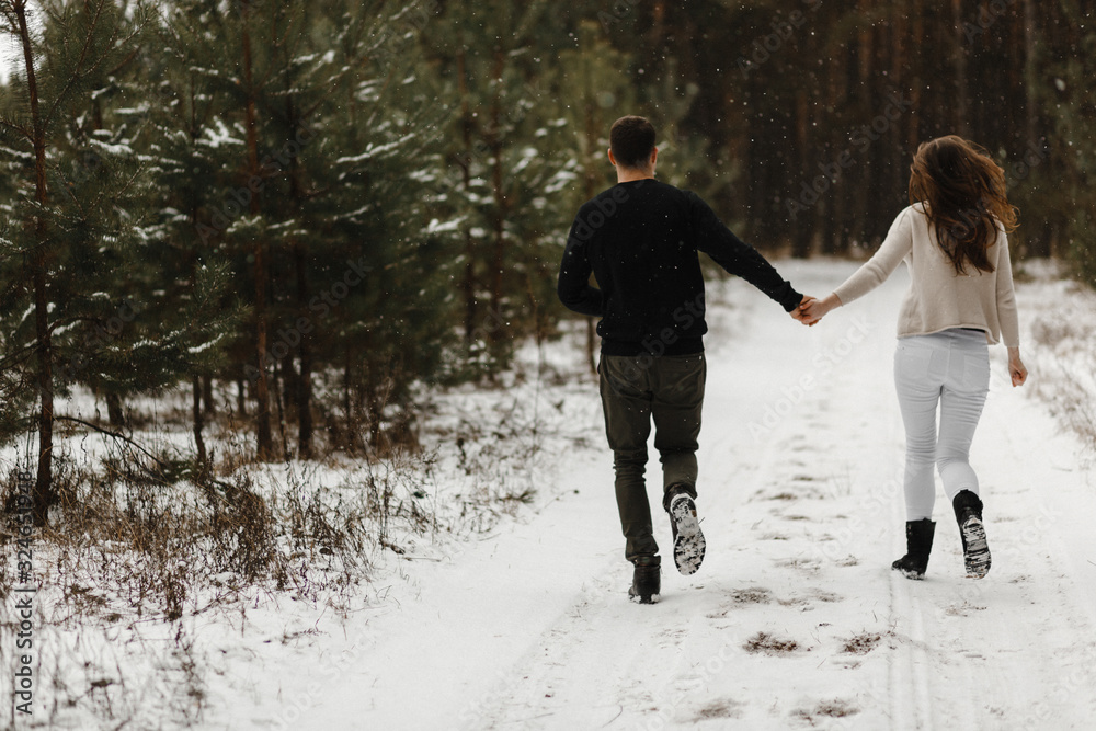 Young couple running in the winter forest Young couple running in the winter forest