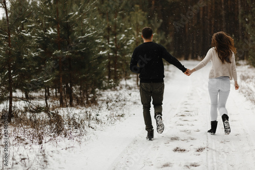 Young couple running in the winter forest