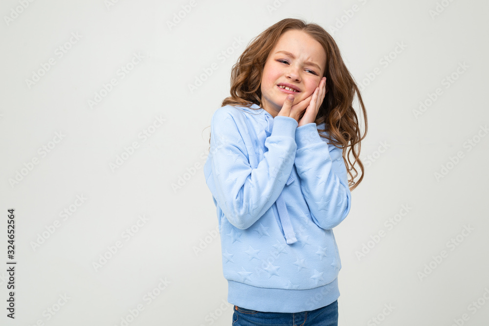 charming teenager girl in a blue hoodie holds his hands by the chin on a white background charming teenager girl in a blue hoodie holds his hands by the chin on a white background