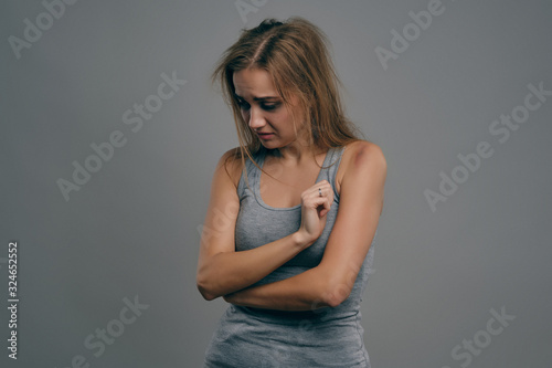 Blonde girl with bruises on her face posing against gray studio background. Domestic violence, abuse. Depression, despair. Close-up, copy space.