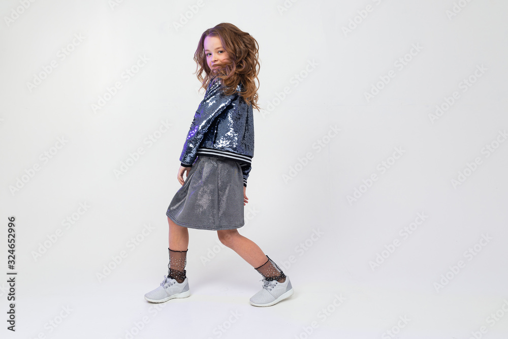Stylish European girl in a beautiful image dances in full growth on a light studio background with copy space Stylish European girl in a beautiful image dances in full growth on a light studio background with copy space