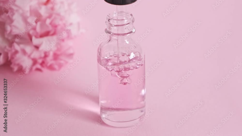Bottle with a pipette gaining oil or perfume essence. Rose oil, flower extract. Skin care. Close up. Bottle with a pipette gaining oil or perfume essence. Rose oil, flower extract. Skin care. Close up.