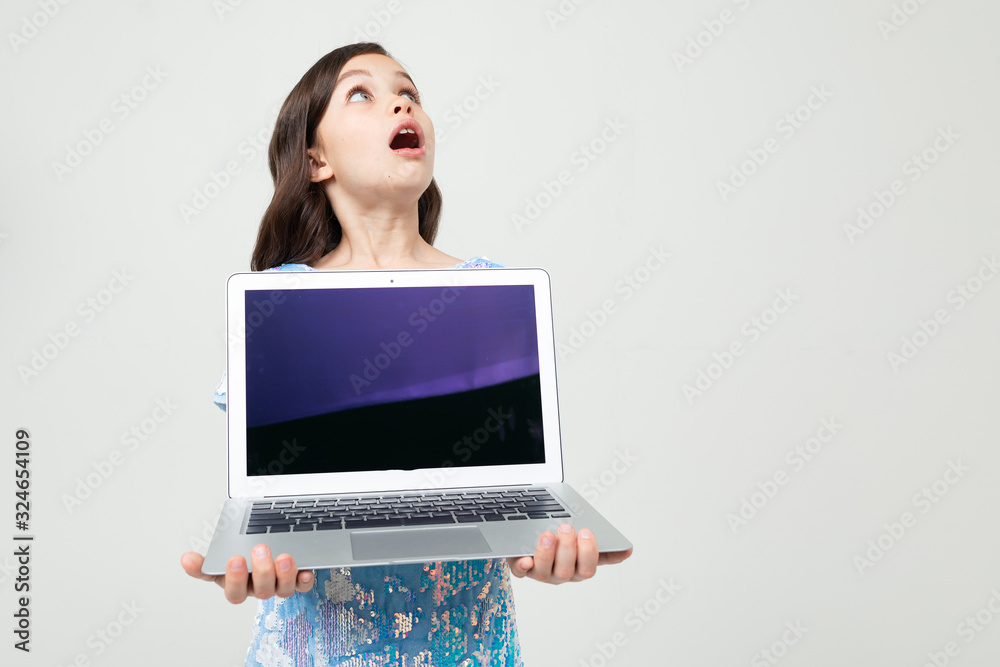 portrait of a surprised teenager girl holding a laptop with a blank screen to insert a website on a white studio background portrait of a surprised teenager girl holding a laptop with a blank screen to insert a website on a white studio background