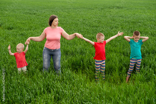 Happy mother with children playing on a green field with wheat..Unity with nature concept