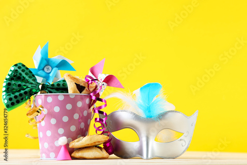 Purim holiday composition. Cookies with bucket and party supplies on yellow background