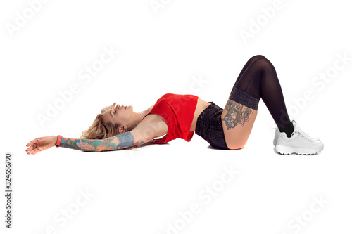 Sexy blond twerk woman with tattoed body and long curly hair is posing in studio. photo