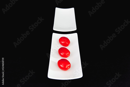 Red cherry tomatoes on the white table and blacxk background. photo