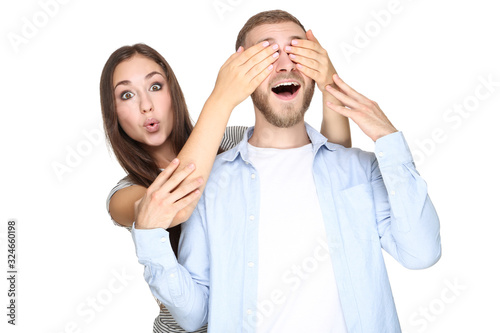 Beautiful woman closing eyes of her man on white background