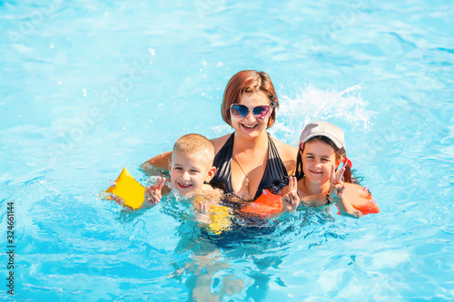beautiful young mother with little son and daughter in pool. © Angelov