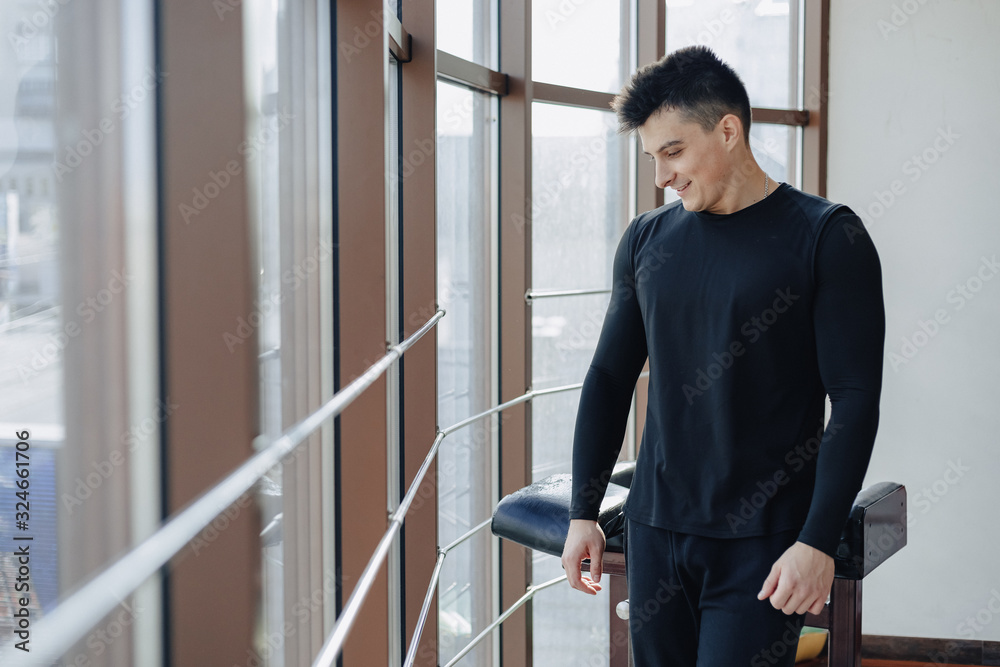 attractive sporty guy by the window. athlete posing near spacious windows. gym and sports. attractive sporty guy by the window. athlete posing near spacious windows. gym and sports.