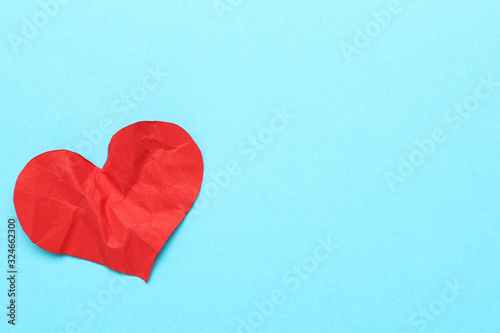 Red crumbled paper heart on blue background