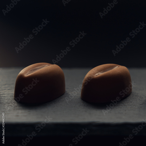 Two pieces of Coffee bean shape Chocolate on black stone plate