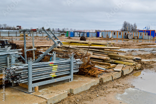 A lot of building materials with metal spare parts, sticks, beams, pipes at an open-air construction site warehouse