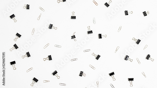 bunch of black binder clips for documents randomly scattered on white background. many stationery clips isolated flat lay. top view of office equipment