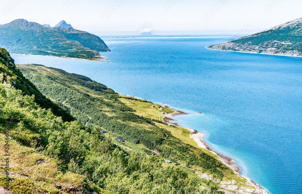 View from high point at calm bay in Norway, close to Nesna town, Hugla island at front left with Donna behind it in blue water of Atlantic ocean, Calm sunny summer day Norway.