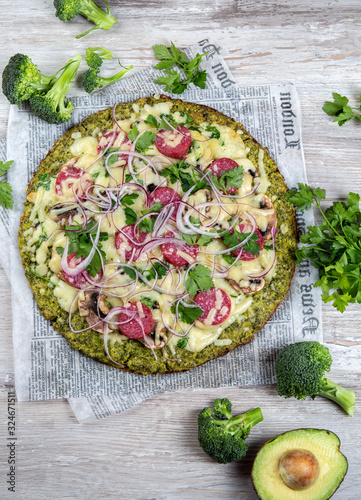 Crust Broccoli base low carbs keto pizza with salami, avocado on vintage newspapper. Top view photo