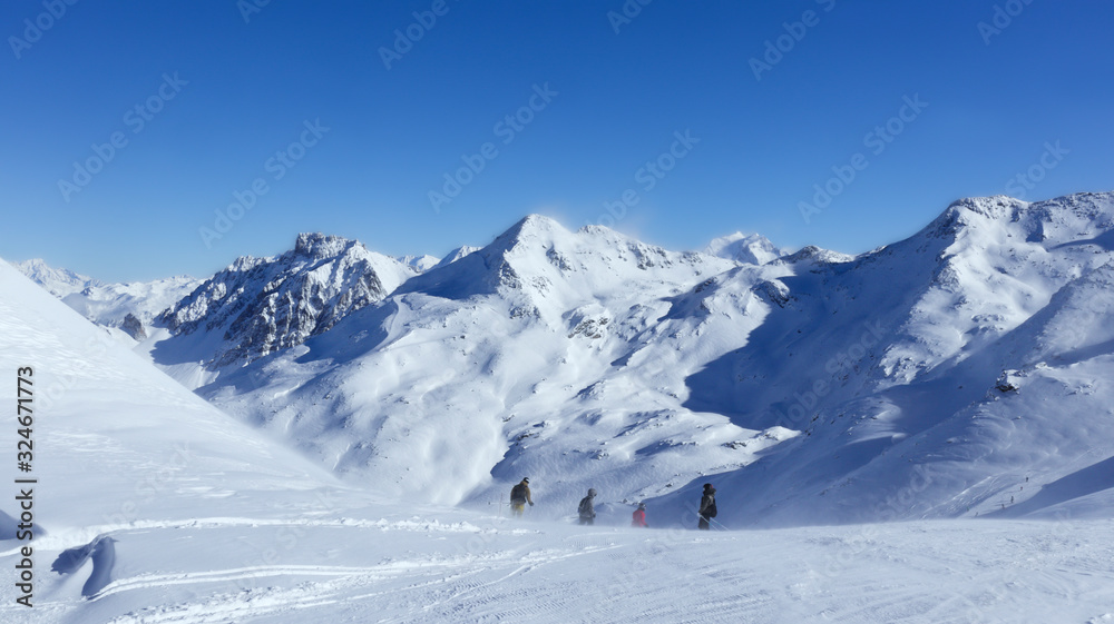 Skiers on top of snowy slope on a windy day, in skiing resort of 3 Valleys, Val Thorens , Alps, France .