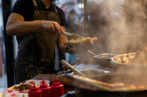 Street food, barbecuing on a hot grill with fire and smoke, thai food, vegetables and meat cooked for taking out. Brick Lane Food Market