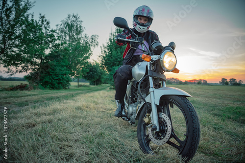 Fototapeta Naklejka Na Ścianę i Meble -  young attractive woman on motorcycle on dirt road at sunset