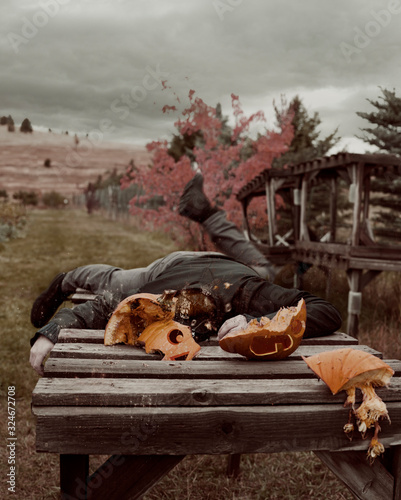 Pumpkin man with smashed pumpkin head lays on outdoor table photo