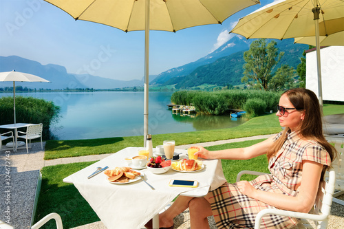 Breakfast of young woman in Luxury street terrace restaurant at Caldaro Lake in Italy