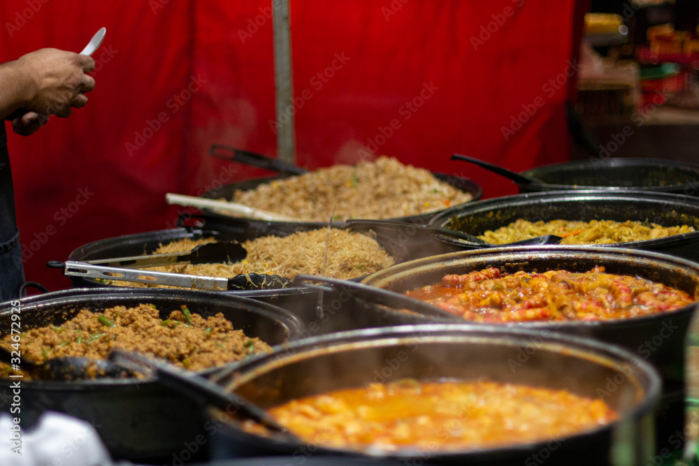 Street food, barbecuing on a hot grill with fire and smoke, thai food, vegetables and meat cooked for taking out. Brick Lane Food Market Street food, barbecuing on a hot grill with fire and smoke, thai food, vegetables and meat cooked for taking out. Brick Lane Food Market