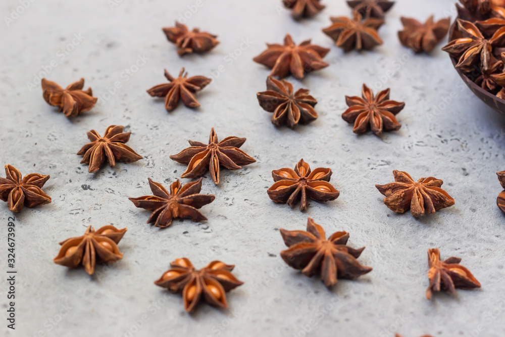 Coconut shell with anise stars and anise stars on grey stone background. Dry brown Anise stars seeds, aromatic Asian spices ingredient in cooking. Food background.