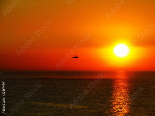 Helicopter over the sea at sunset