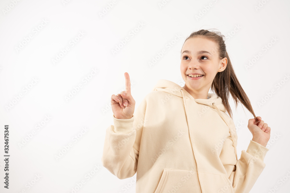Excited female in beige hoodie pointing and looking up, isolated over white background Excited female in beige hoodie pointing and looking up, isolated over white background