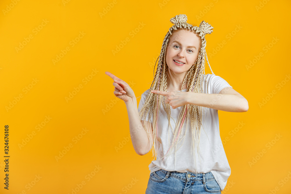 Joyful young caucasian woman in casual is pointing to empty space, isolated in yellow background