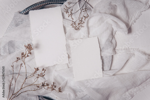 Wedding invitation mockup with dry plants , papers on white textile background. Top view, flat lay. Wedding stationary. Perfect for presentation of your invitation, menu, greeting cards