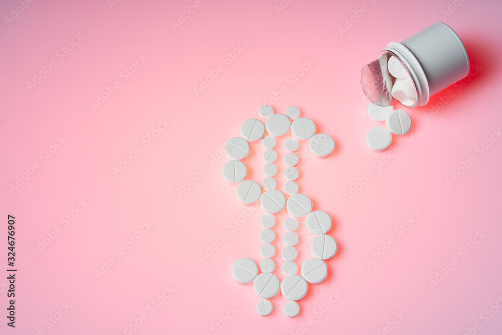 Dollar mark made by white pills spilling out of white bottle on pink background. Creative medicine for health/medical problem, medication error, drug information and pharmacy concept. Copy space. Dollar mark made by white pills spilling out of white bottle on pink background. Creative medicine for health/medical problem, medication error, drug information and pharmacy concept. Copy space.