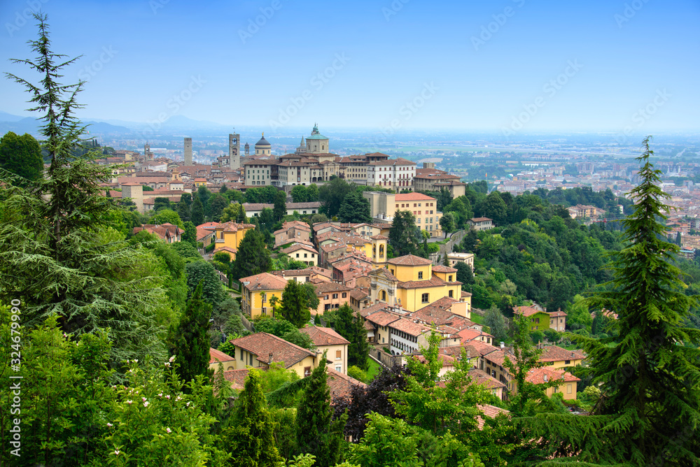 Paesaggio urbano di Bergamo con le case antiche dall'alto e le zone erbose ed alberi con contrasto del cielo