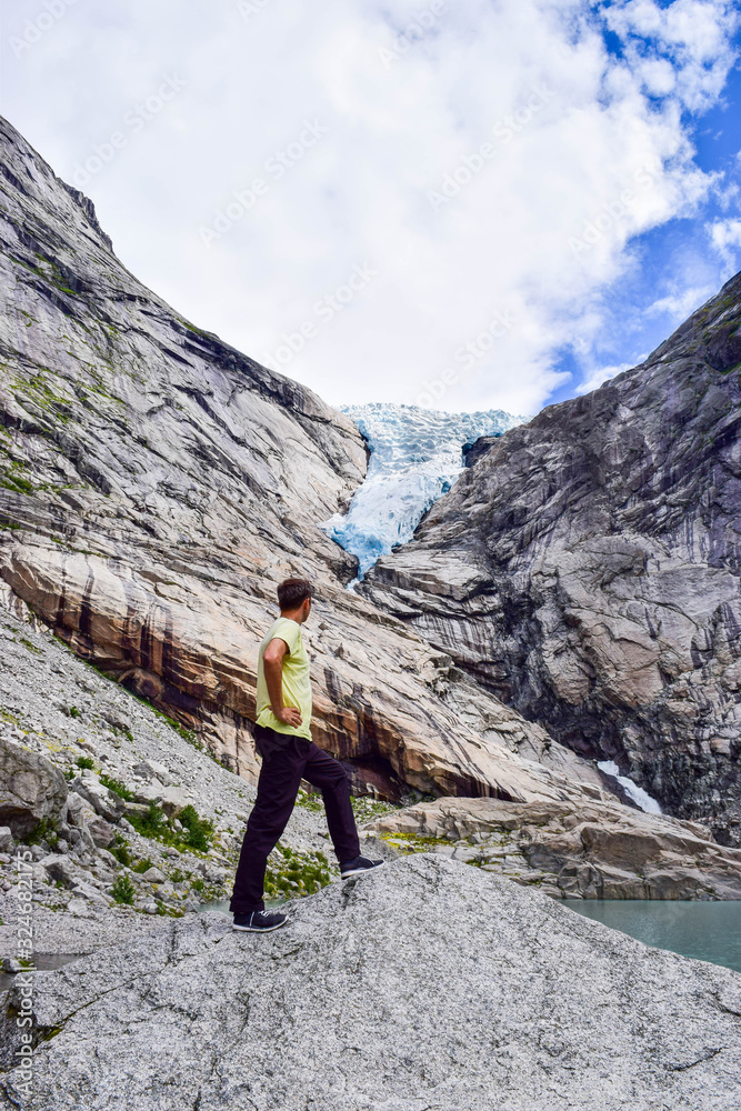 The man near the Briksdalsbreen (Briksdal) glacier, which is the sleeve of large Jostedalsbreen glacier. Melting glacier forms the Briksdalsbrevatnet lake with clear water. Norway.
