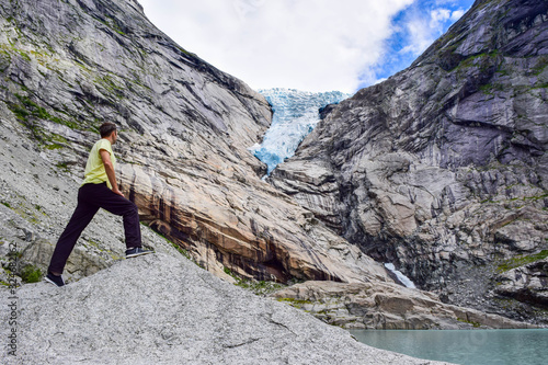 The man near the Briksdalsbreen (Briksdal) glacier, which is the sleeve of large Jostedalsbreen glacier. Melting glacier forms the Briksdalsbrevatnet lake with clear water. Norway.