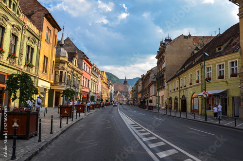 Old street with ancient buildings and stone paved road in Brasov city center  Romania. The Black Church can be seen up above.