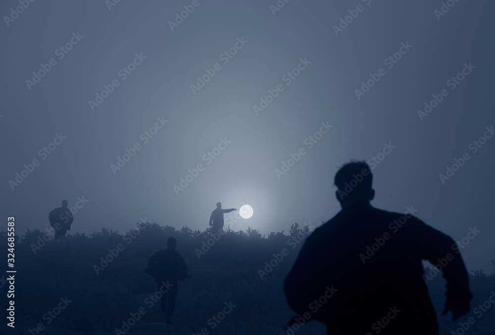 Fototapeta premium silhouette of men running towards setting sun, artistic image