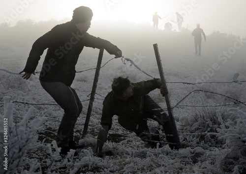 Two men escape from enemies through fence photo