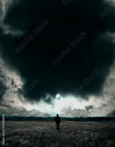 Man standing in dark field with moonlit sky above