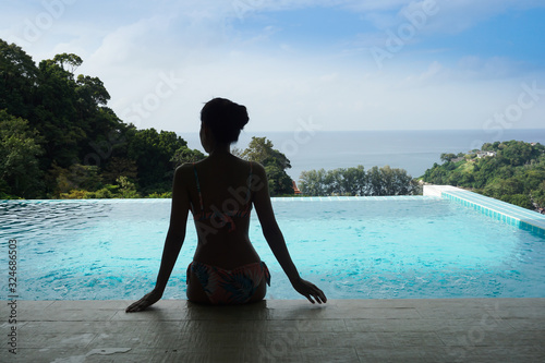 Woman sitting on the edge of the swimming pool, preparing to swim.