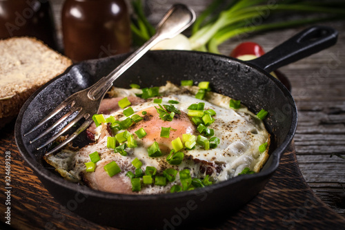 Fried eggs with ham on an old wooden background.