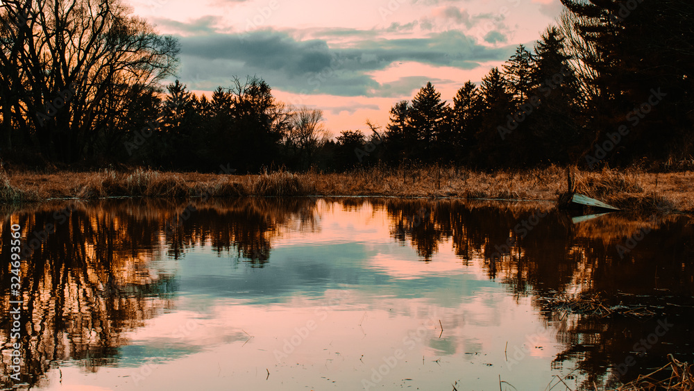 Fototapeta premium An Orange and Blue Sunset Reflecting Off of a Lake
