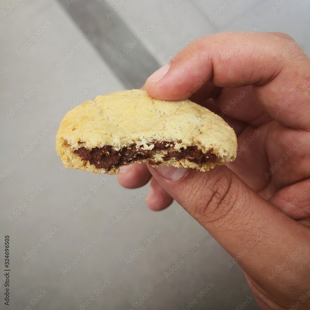man's hand holding a half eaten chocolate chip cookie man's hand holding a half eaten chocolate chip cookie