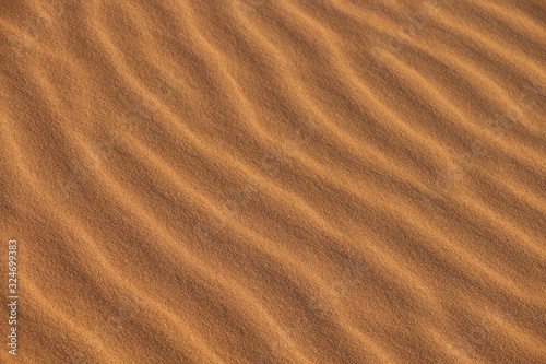 sand texture - background of desert sand dunes. Beautiful structures of sandy dunes. sand with wave from wind in desert - Close up © Ayman