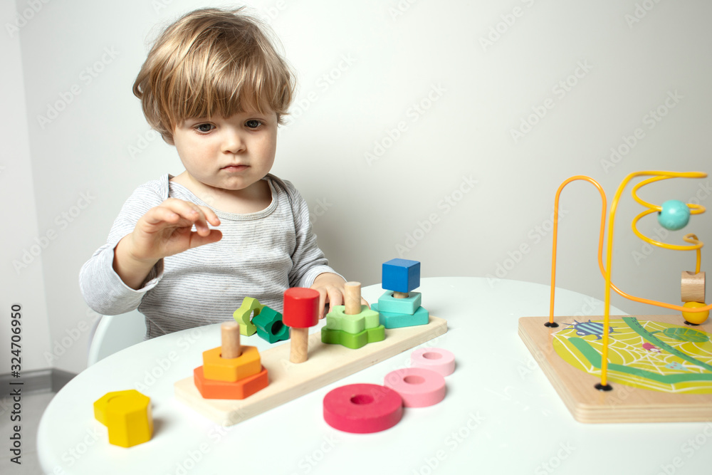 Beautiful toddler play with a wooden toys at home. Toddler play with a color educational toy. Child play at the table in the baby room. Child development. Funny baby. Lifestyle. Beautiful toddler play with a wooden toys at home. Toddler play with a color educational toy. Child play at the table in the baby room. Child development. Funny baby. Lifestyle.